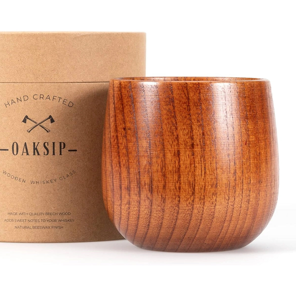 A Finished Beech Wood Bourbon/Whiskey Drinking Glass is positioned next to a cylindrical cardboard container. The container, labeled "Oaksip Finished Beech Wood Bourbon/Whiskey Drinking Glass," features small crossed ax illustrations. The glass has smooth, polished wood with visible grain patterns, showcasing its unique design.