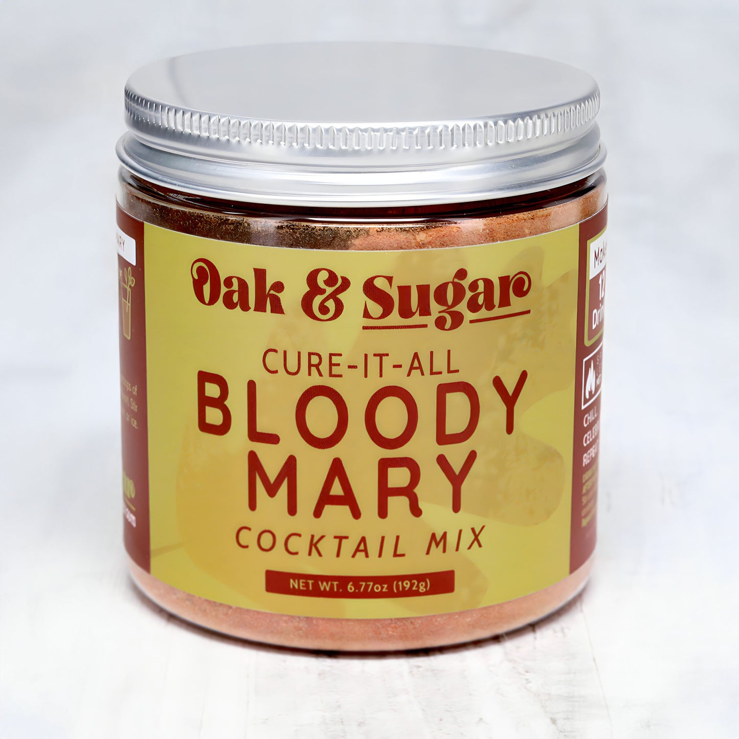 A jar of Oak & Sugar Cure-It-All Bloody Mary Cocktail Mix is displayed against a light background. The jar has a silver lid and a red label with yellow text. Perfect for your next brunch cocktail, the net weight is 6.77 oz (192 g).